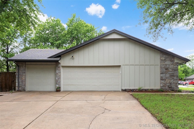 garage featuring concrete driveway and fence