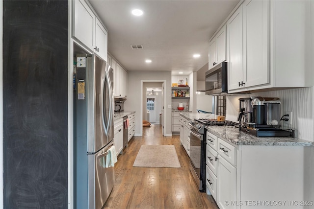 kitchen with stainless steel appliances, visible vents, recessed lighting, white cabinets, and light wood-style floors