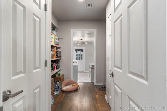 hall with visible vents, wood finished floors, and baseboards