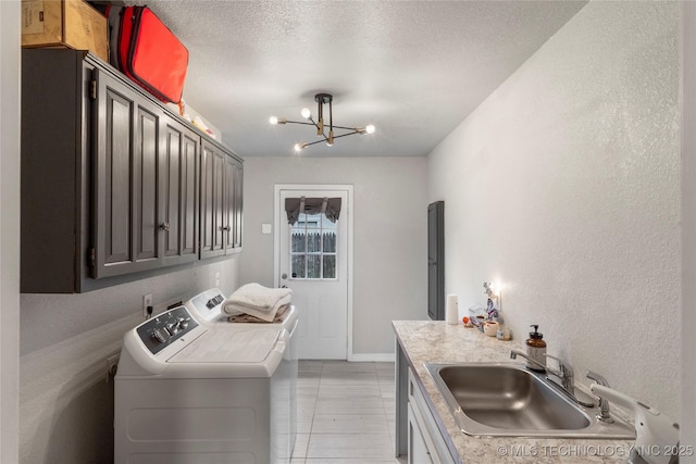 washroom featuring washing machine and dryer, a sink, a notable chandelier, a textured ceiling, and baseboards