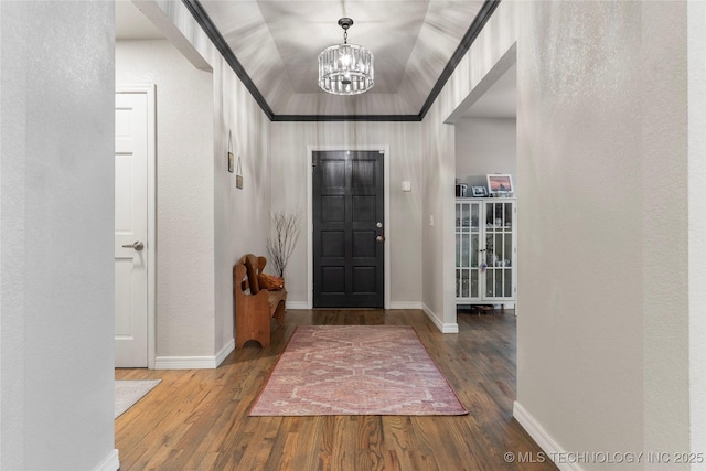entrance foyer featuring a textured wall, a notable chandelier, baseboards, and wood finished floors