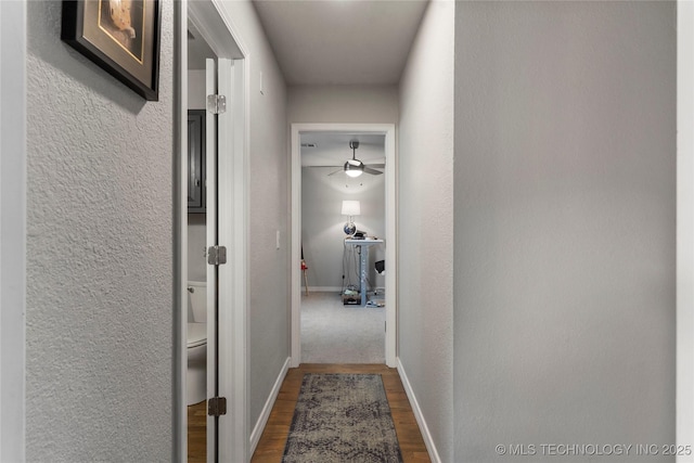 hall with baseboards, dark wood-style floors, and a textured wall