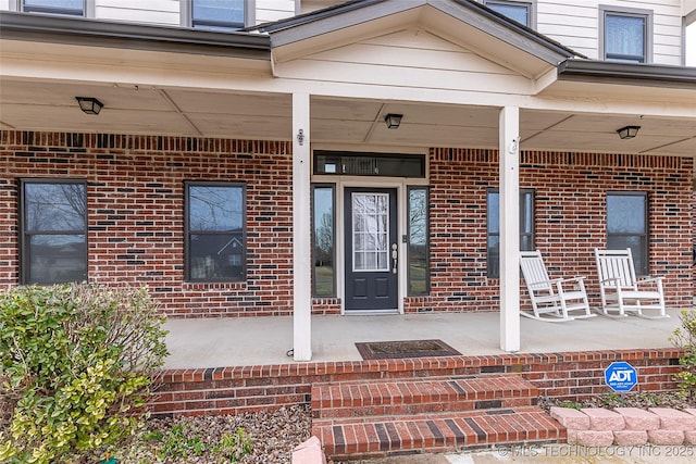 entrance to property featuring covered porch and brick siding