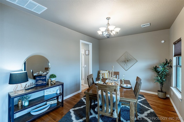dining room with a notable chandelier, visible vents, and wood finished floors