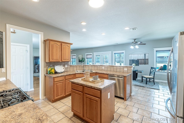 kitchen with a peninsula, a sink, stainless steel appliances, backsplash, and light countertops