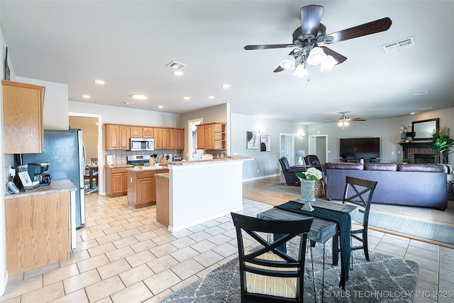 12285 N 164th E Pl, Collinsville, OK 74021 - kitchen with a ceiling fan, appliances with stainless steel finishes, light countertops, open floor plan, and decorative backsplash