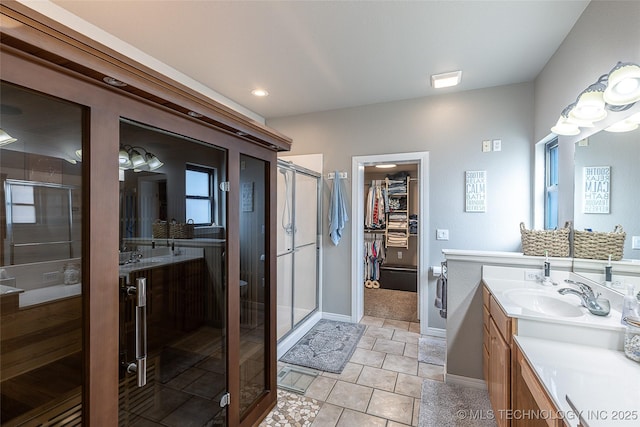 bathroom with a stall shower, a sink, tile patterned flooring, two vanities, and a walk in closet