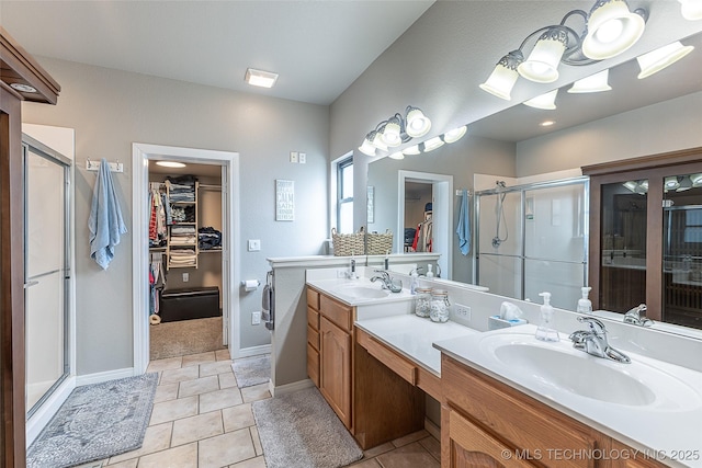 bathroom featuring a sink, a stall shower, tile patterned flooring, a spacious closet, and double vanity