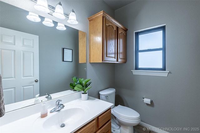 half bathroom with toilet, baseboards, and vanity