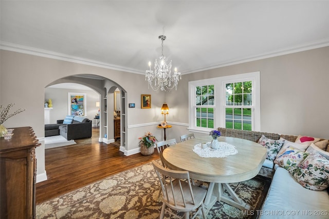 dining area featuring an inviting chandelier, crown molding, arched walkways, and wood finished floors