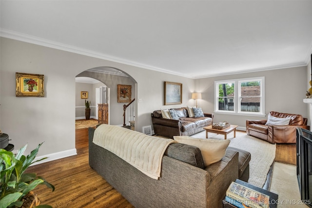 living room with crown molding, wood finished floors, baseboards, and arched walkways