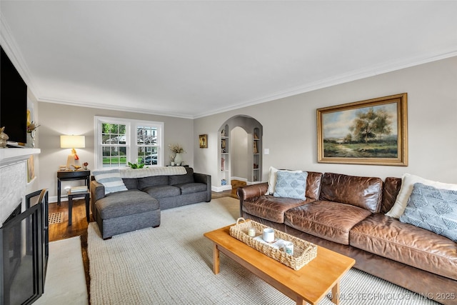 living area with ornamental molding, arched walkways, baseboards, and wood finished floors
