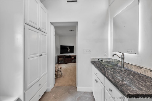 bathroom featuring visible vents, baseboards, and vanity