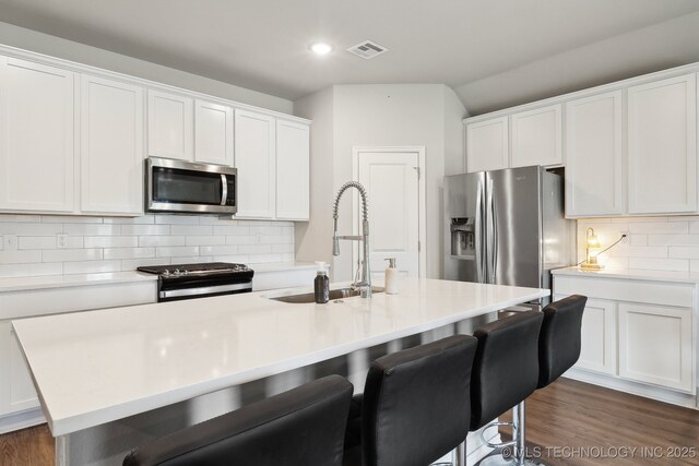 4218 W Village Park Dr, Skiatook, OK 74070 - kitchen with a sink, a kitchen bar, decorative backsplash, light countertops, and appliances with stainless steel finishes