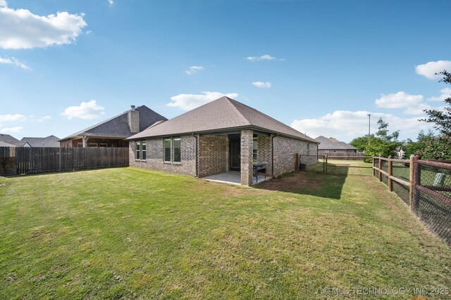 4218 W Village Park Dr, Skiatook, OK 74070 - rear view of house featuring a shingled roof, a fenced backyard, a yard, brick siding, and a patio area