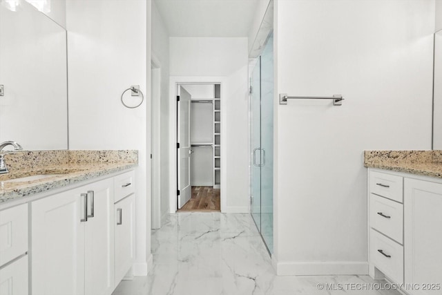 13242 E 4th Pl, Tulsa, OK 74108 - bathroom featuring a sink, marble finish floor, a stall shower, a walk in closet, and baseboards