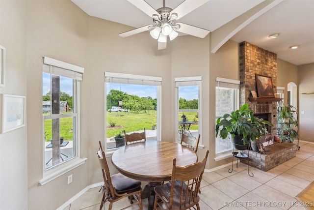 dining area with arched walkways, baseboards, and high vaulted ceiling