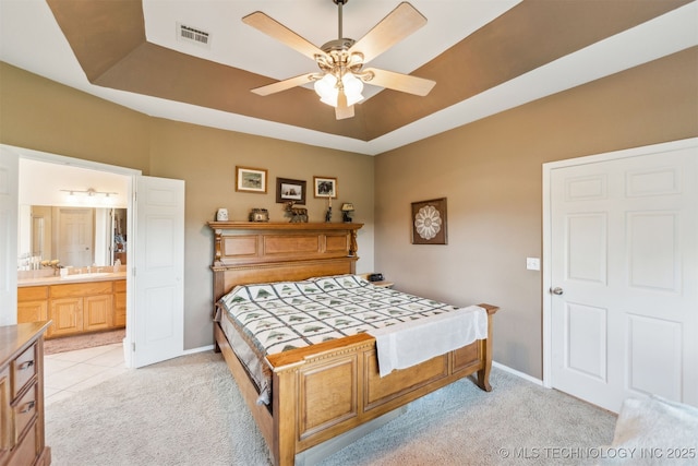 bedroom featuring a tray ceiling, light carpet, baseboards, and visible vents