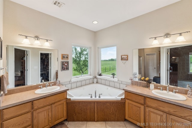 full bathroom featuring a sink, a tub with jets, two vanities, and visible vents
