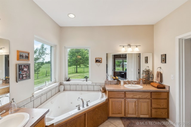 full bathroom with a wealth of natural light, tile patterned flooring, a jetted tub, and vanity