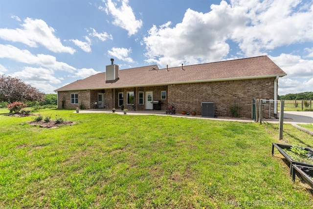 rear view of house featuring a patio area, brick siding, cooling unit, a chimney, and a lawn