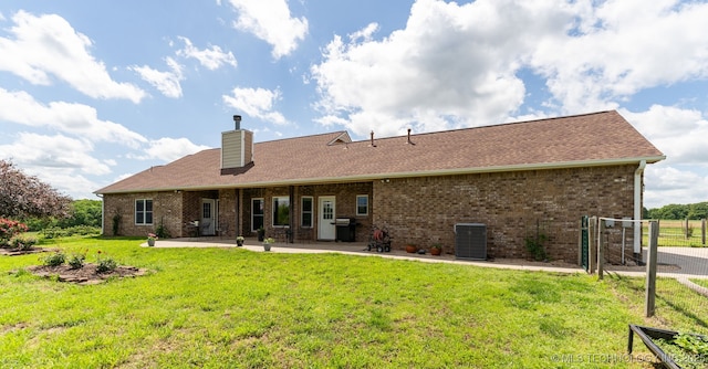 rear view of house featuring central AC unit, a patio area, a chimney, and brick siding