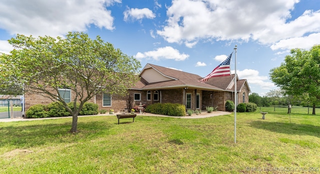 view of front facade featuring brick siding, a front lawn, and fence