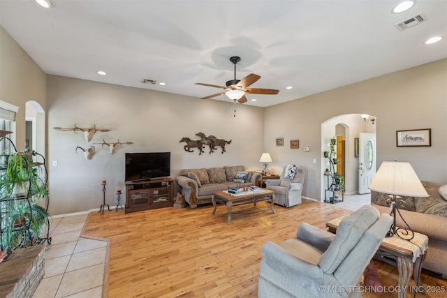 living room with visible vents, recessed lighting, light wood-style flooring, arched walkways, and a ceiling fan