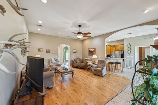 living room featuring a ceiling fan, recessed lighting, light tile patterned flooring, visible vents, and arched walkways
