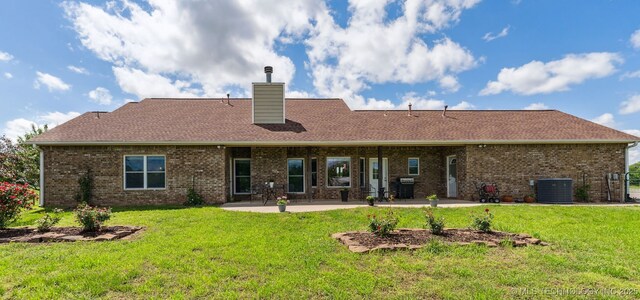 back of property featuring brick siding, central AC, a yard, a patio, and a chimney