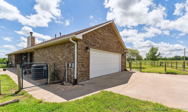 view of side of home featuring central air condition unit, brick siding, a gate, and fence