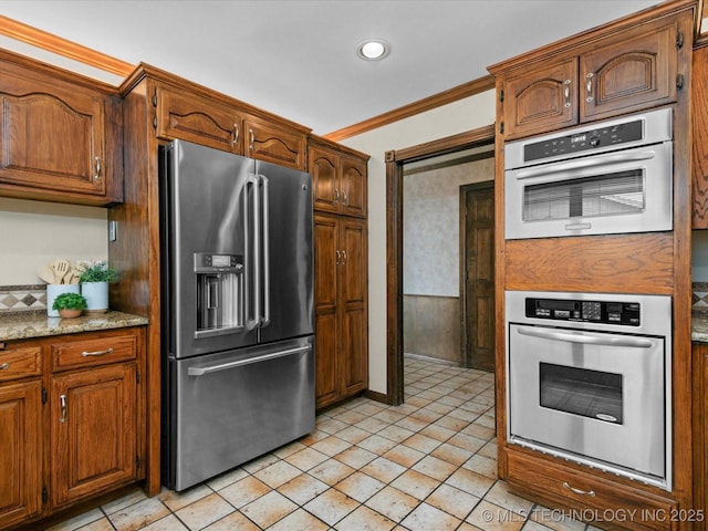 2600 Chapel Hill Rd, Bartlesville, OK 74006 - kitchen with appliances with stainless steel finishes, ornamental molding, brown cabinetry, recessed lighting, and light stone counters