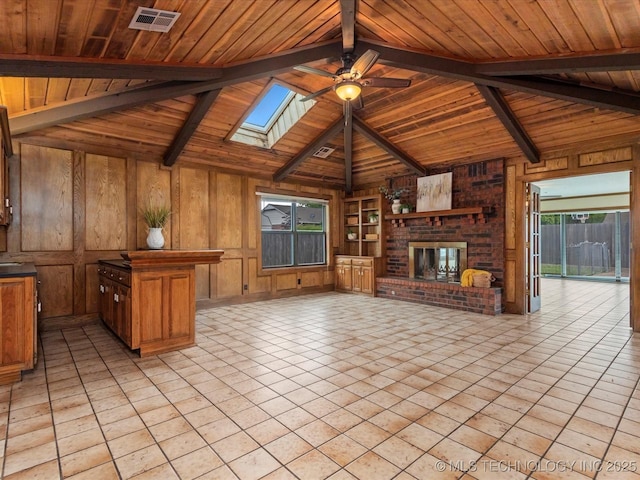 2600 Chapel Hill Rd, Bartlesville, OK 74006 - unfurnished living room featuring wooden walls, ceiling fan, wood ceiling, a brick fireplace, and a skylight