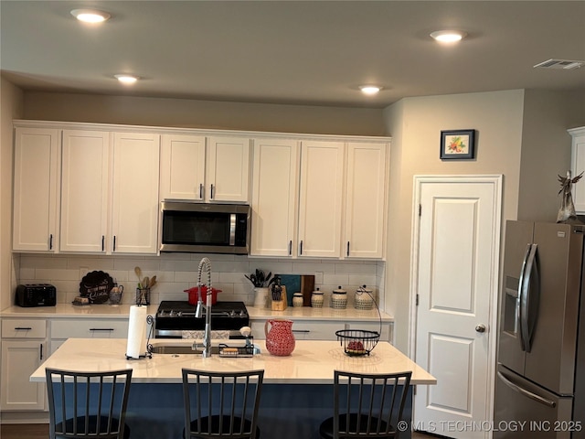 4242 W Village Park Dr, Skiatook, OK 74070 - kitchen featuring tasteful backsplash, white cabinets, visible vents, and appliances with stainless steel finishes
