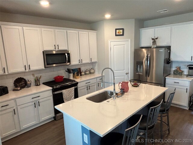 4242 W Village Park Dr, Skiatook, OK 74070 - kitchen with a sink, backsplash, dark wood-style floors, white cabinets, and appliances with stainless steel finishes