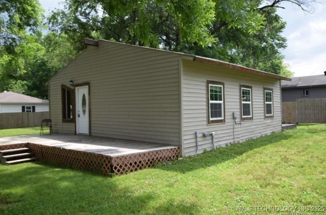 back of property with a yard, a deck, and fence