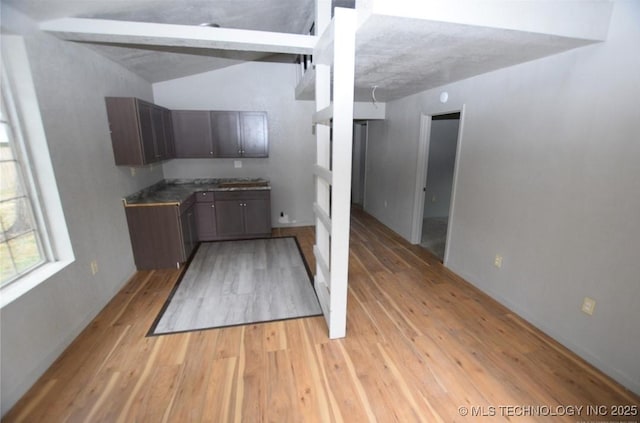 kitchen featuring dark brown cabinets, baseboards, and light wood finished floors
