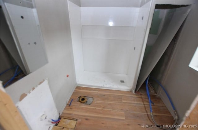 bathroom featuring wood finished floors and a shower stall