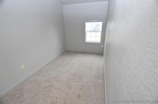carpeted empty room featuring baseboards