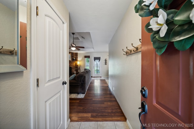 hall with a raised ceiling, tile patterned flooring, and baseboards