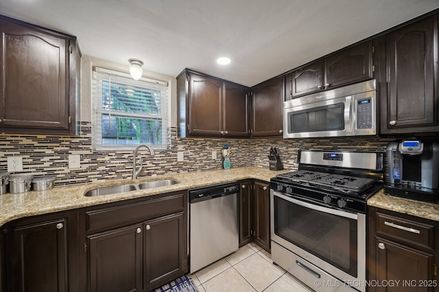 kitchen with stainless steel appliances, a sink, dark brown cabinetry, tasteful backsplash, and light tile patterned flooring