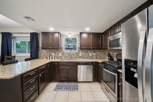 kitchen featuring stainless steel appliances, a sink, light tile patterned floors, dark brown cabinets, and recessed lighting