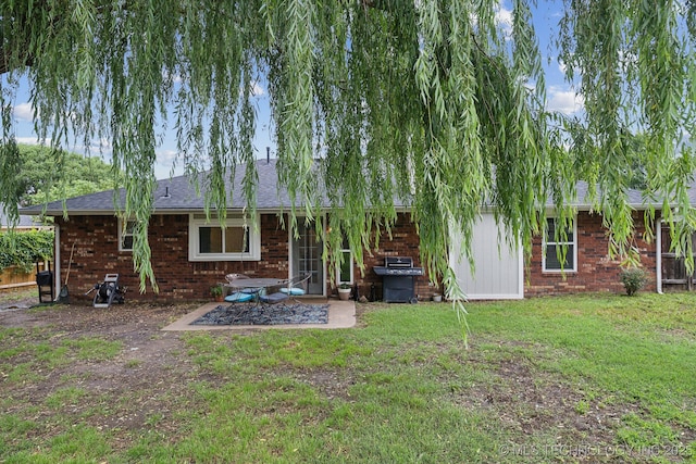 back of house featuring a yard, brick siding, and a patio