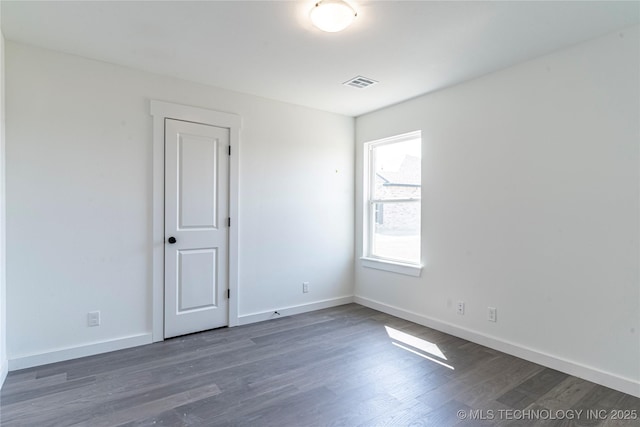 unfurnished room featuring baseboards, visible vents, and wood finished floors