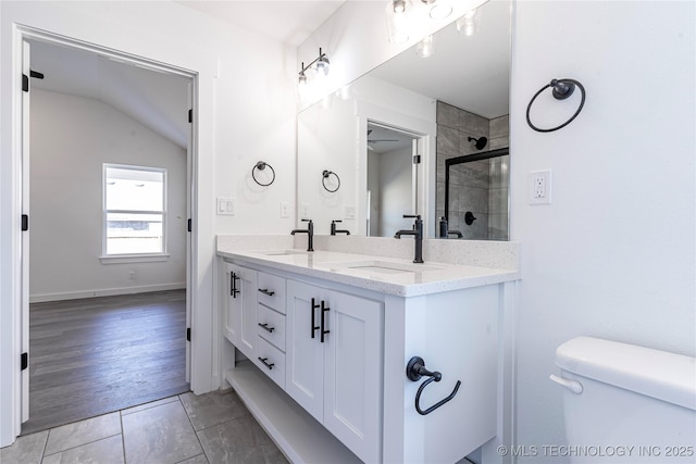 bathroom with a stall shower, toilet, a sink, and double vanity