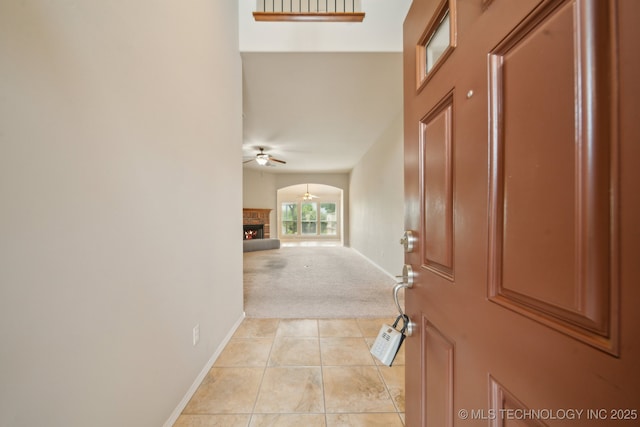4712 N Narcissus Ave, Broken Arrow, OK 74012 - foyer entrance featuring a ceiling fan, light carpet, light tile patterned floors, a warm lit fireplace, and baseboards
