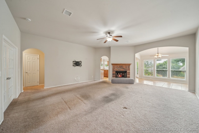 4712 N Narcissus Ave, Broken Arrow, OK 74012 - unfurnished living room with a ceiling fan, arched walkways, light colored carpet, and a brick fireplace