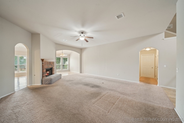 4712 N Narcissus Ave, Broken Arrow, OK 74012 - unfurnished living room featuring arched walkways, ceiling fan, light colored carpet, and a brick fireplace