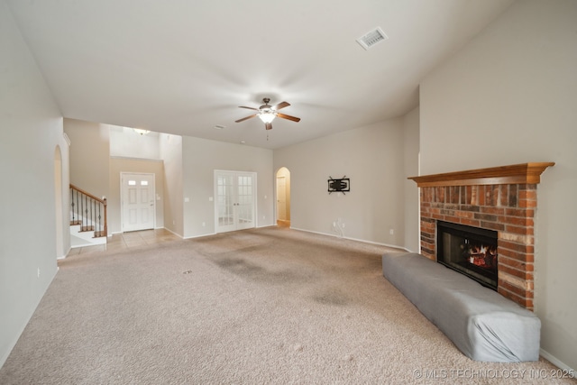4712 N Narcissus Ave, Broken Arrow, OK 74012 - unfurnished living room featuring arched walkways, a brick fireplace, carpet flooring, ceiling fan, and stairs