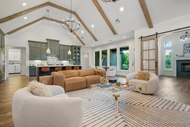 16804 E 43rd St S, Tulsa, OK 74134 - living area featuring washing machine and dryer, a barn door, a chandelier, and high vaulted ceiling